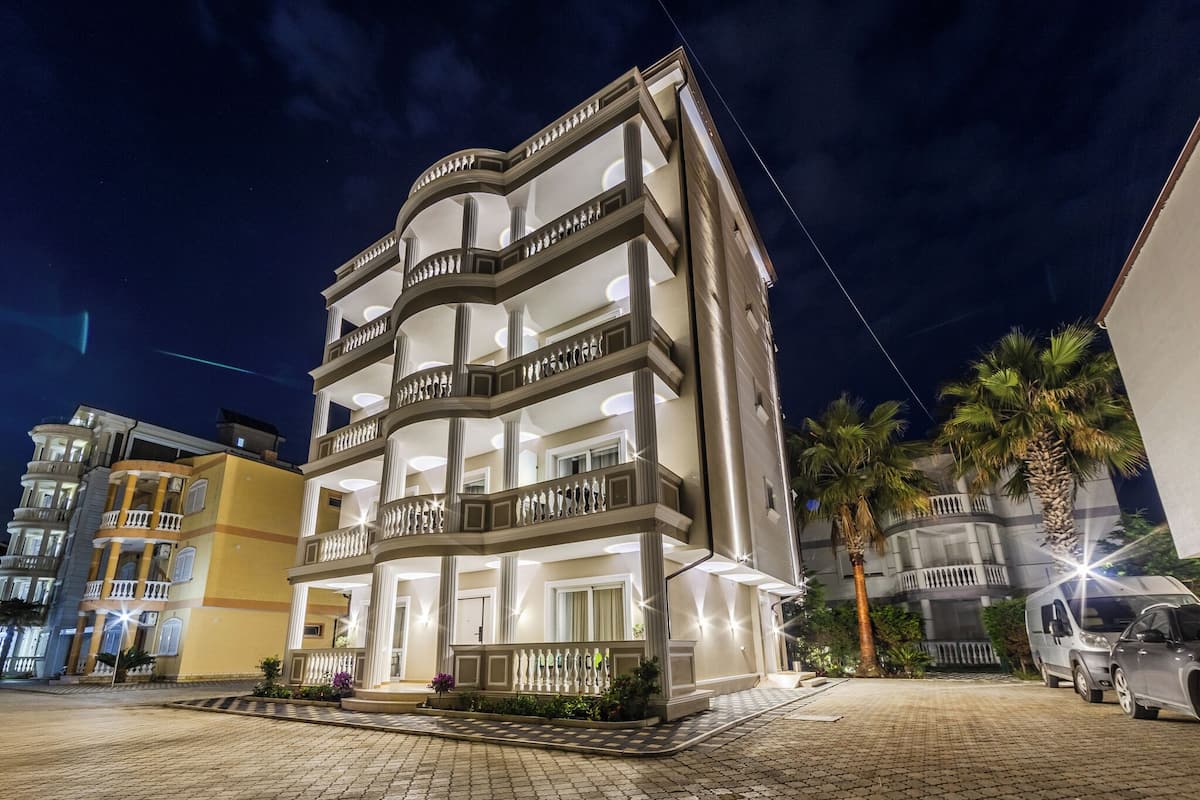 Un edificio de varios pisos con balcones y un área de acceso pavimentada.