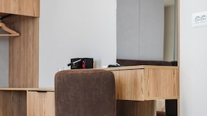 A modern room with a wooden desk, a brown chair, and a built-in bench. - SEA LA VIE SUITES (Golem)