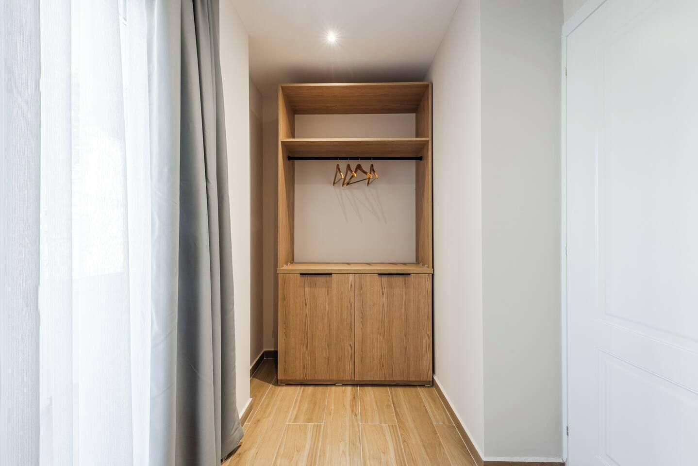 A narrow hallway with a wooden wardrobe and a coat rack.