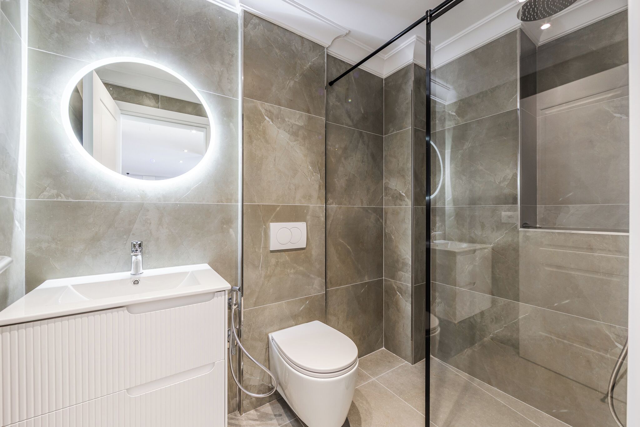 A modern bathroom with a glass shower enclosure, a white sink, and a toilet.