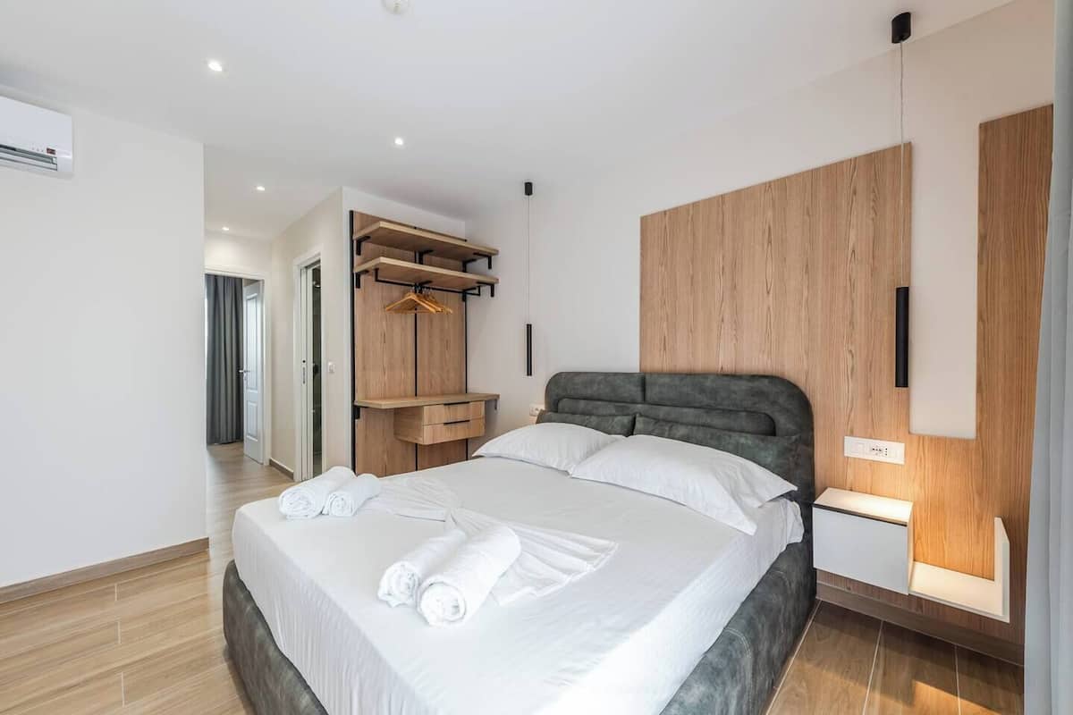 Una habitación de hotel moderna con una cama grande, un armario empotrado y una mesita de noche con lámpara.