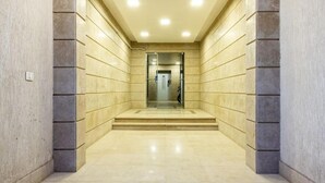 A modern, well-lit hallway with a marble floor and walls, leading to a door at the end. - Kennah Meraviglia | 4BR Stone Residence, New Cairo - Families Only (New Cairo)