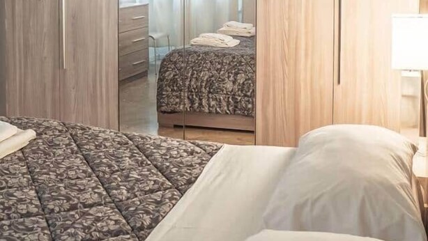 A bedroom with a bed, a wardrobe, and a mirror.