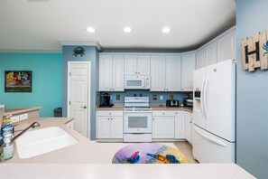 Una cocina con armarios blancos, microondas, estufa y refrigerador.