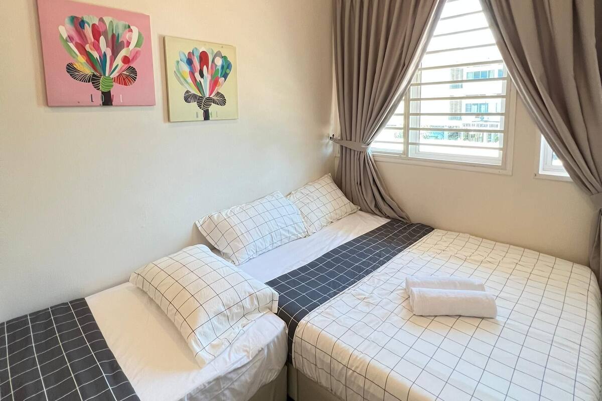 A hotel room with two beds, a window with curtains, and two wall art pieces.