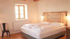 Une chambre à coucher avec un lit, une chaise, une fenêtre et des poutres en bois au plafond.