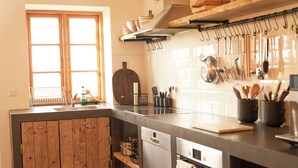 Une cuisine avec des meubles de rangement en bois, un lave-vaisselle et divers ustensiles accrochés au mur.