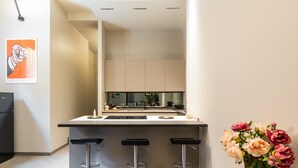 Una cocina moderna con una isla central, tres taburetes de bar y un jarrón con flores.