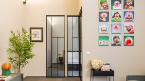 Un interior moderno con un armario espejo, una planta en maceta y una pared decorada con arte colorido.