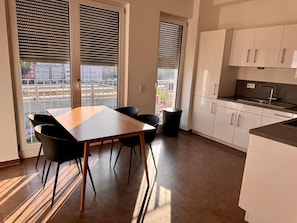 A modern kitchen with white cabinets, a black countertop, and a window with blinds.