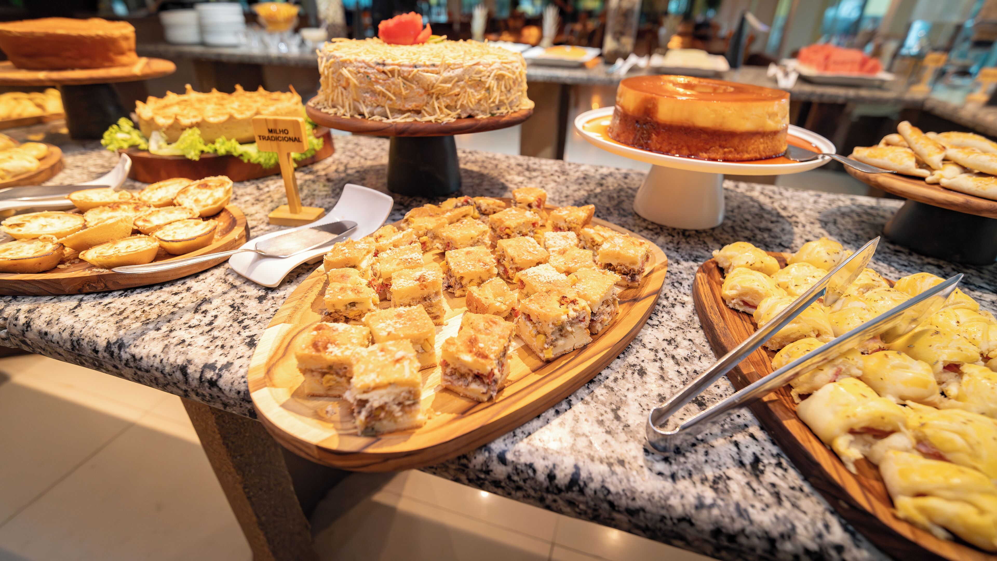 Ein Buffet mit verschiedenen Speisen, darunter traditioneller Kuchen, Vorspeisen aus Mais und eine Auswahl weiterer Gerichte.