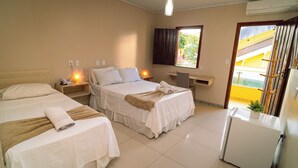 A hotel room with three beds, a desk, a chair, a small table, and a refrigerator. - Pousada Itajuipe (Itabuna)