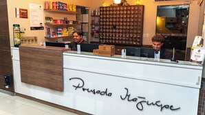 A reception desk with a wooden counter and a glass top. The name 'Prouse da Haja' is displayed on the wall. - Pousada Itajuipe (Itabuna)
