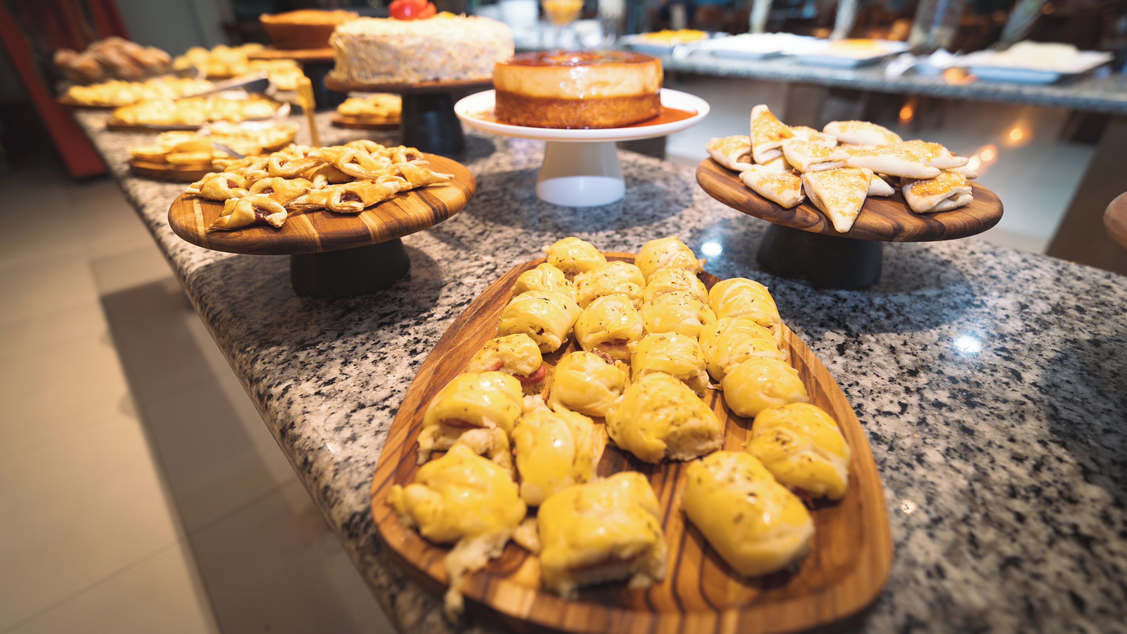 A buffet with various dishes including pies, pastries, and a cake on a granite countertop.