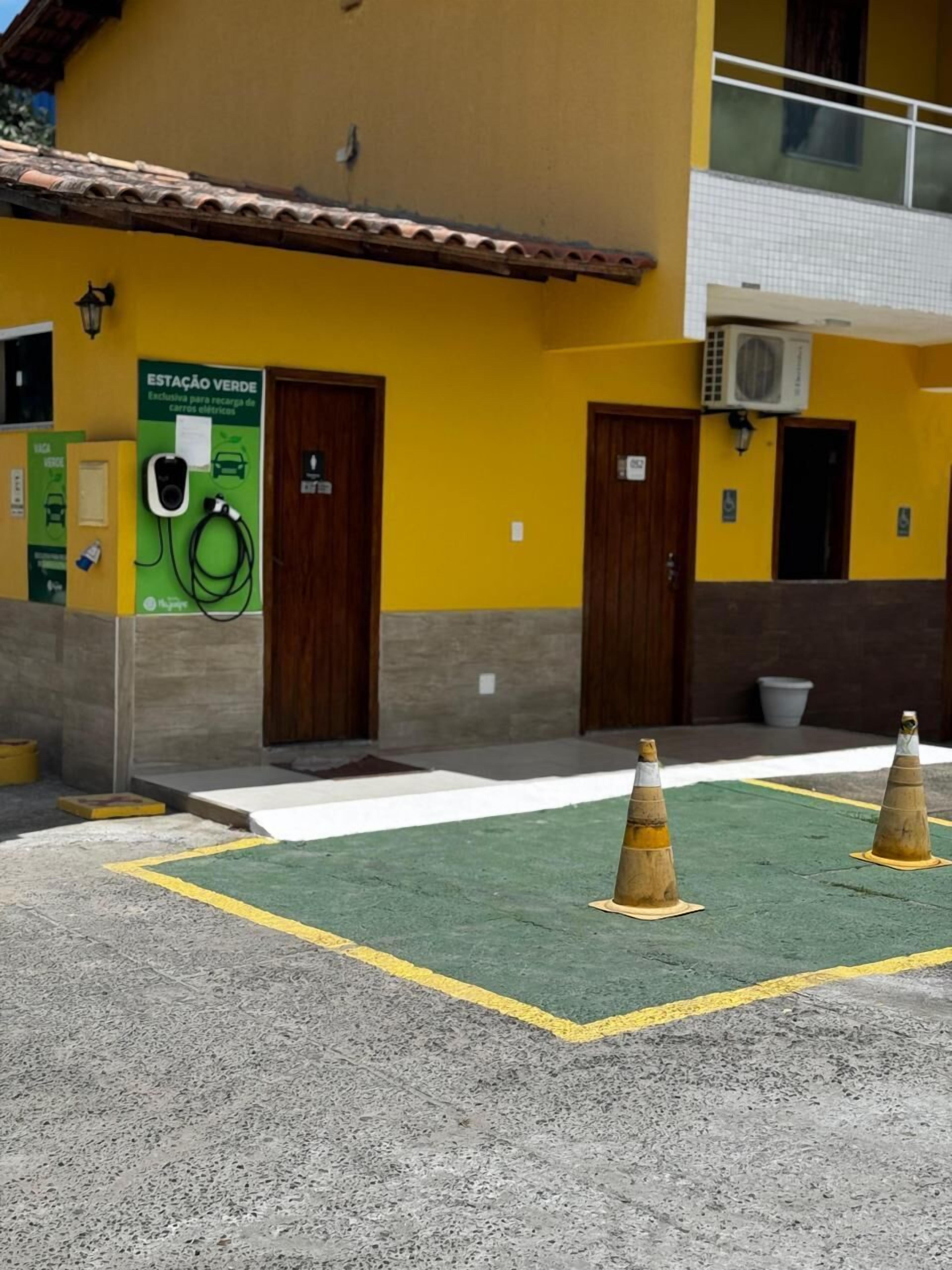 A building with a yellow facade, a green parking area, and a sign indicating a green parking spot for electric vehicles.