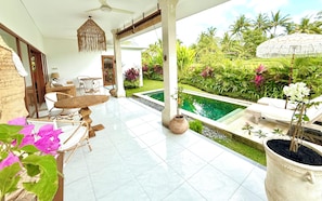 A covered patio with a pool, outdoor furniture, and lush greenery. - Villa Hummingbird Ubud (Ubud)