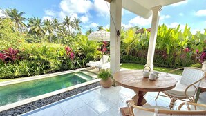 A covered outdoor area with a pool, surrounded by lush tropical plants and palm trees. - Villa Hummingbird Ubud (Ubud)
