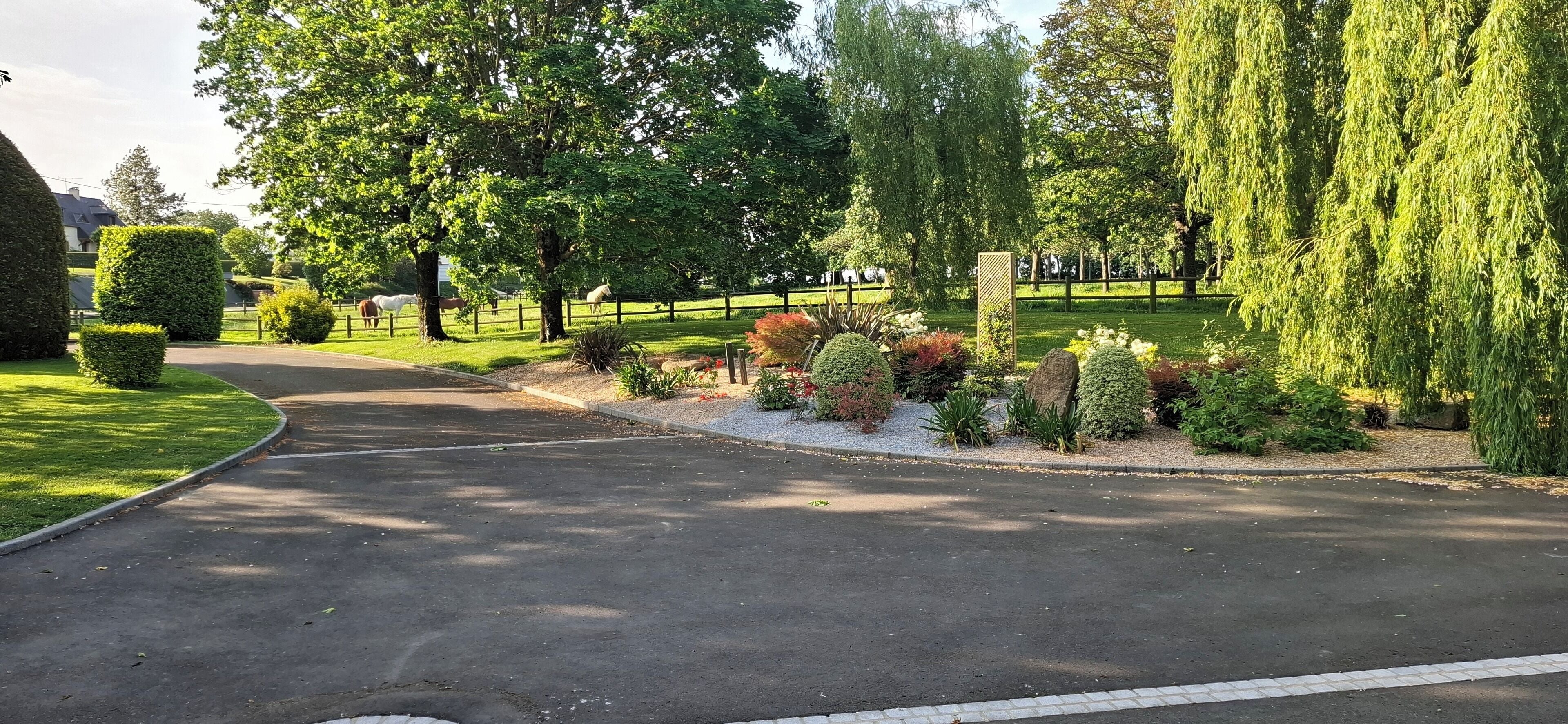 A well-maintained garden with a curved driveway leading to a gated entrance.