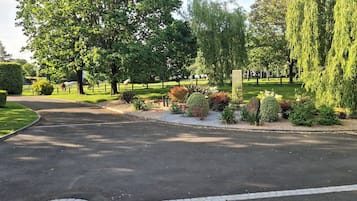 A well-maintained garden with a curved driveway leading to a gated entrance.