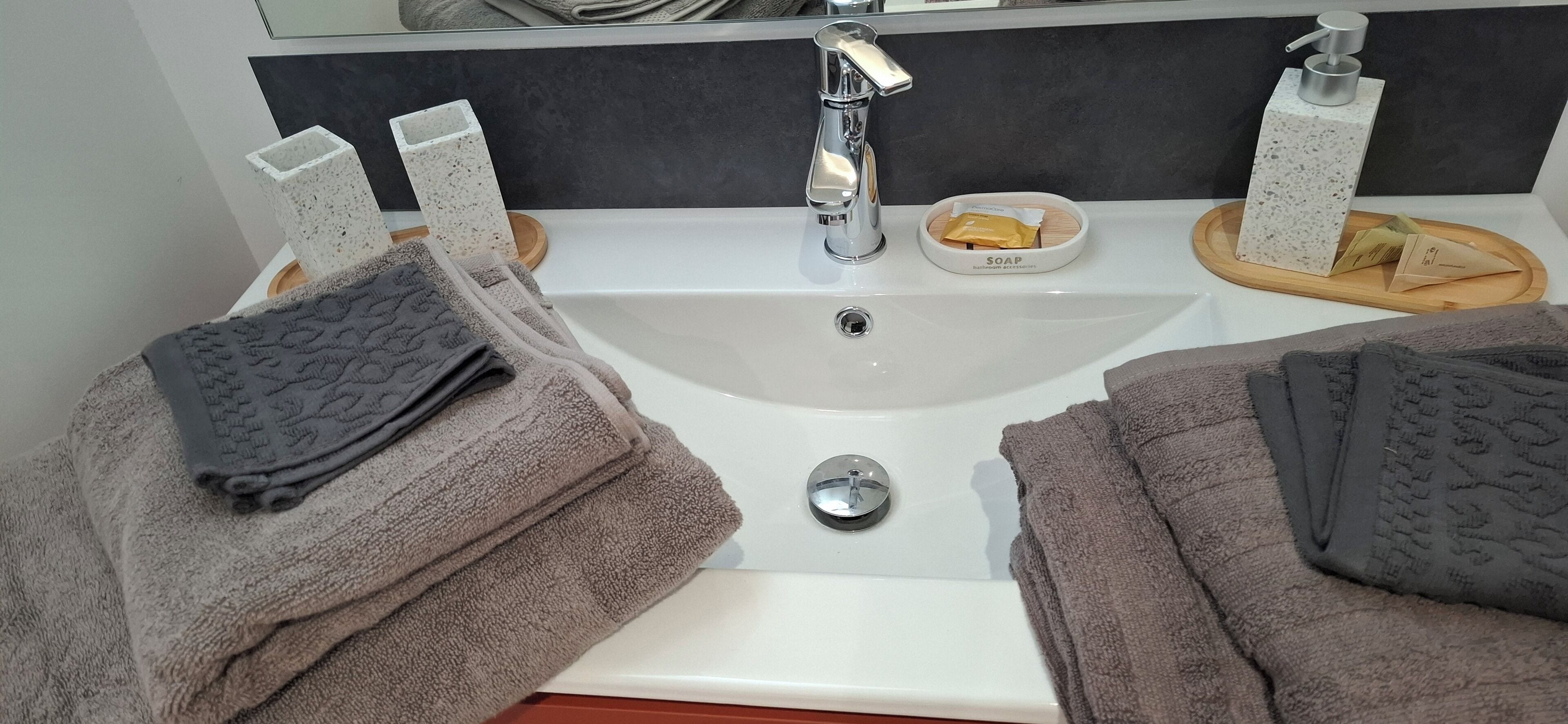 A bathroom with a white sink, two soap dispensers, and a soap dish.