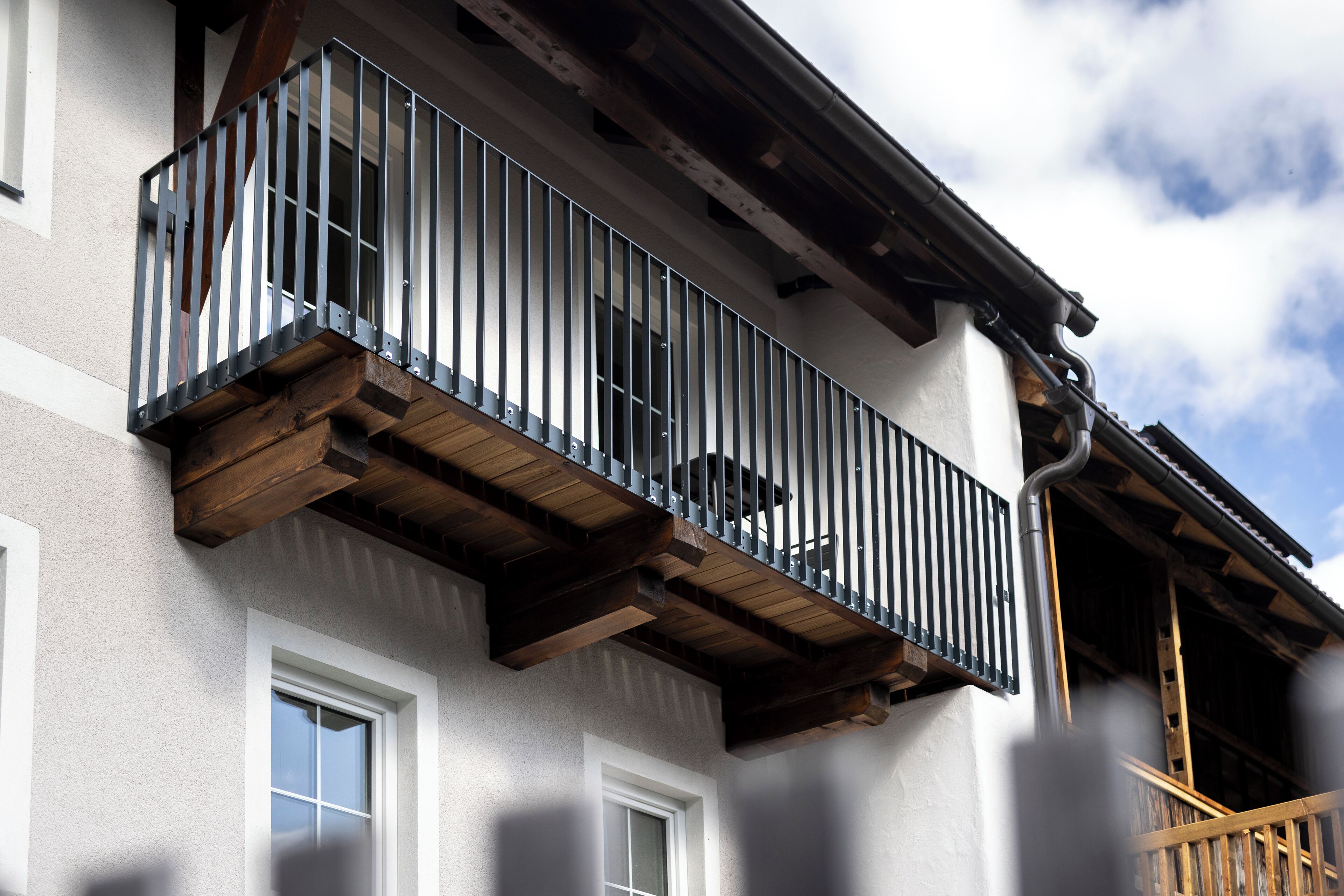 Ein Gebäude mit einem Balkon, der mit Metallgeländern und Holzbalken versehen ist.