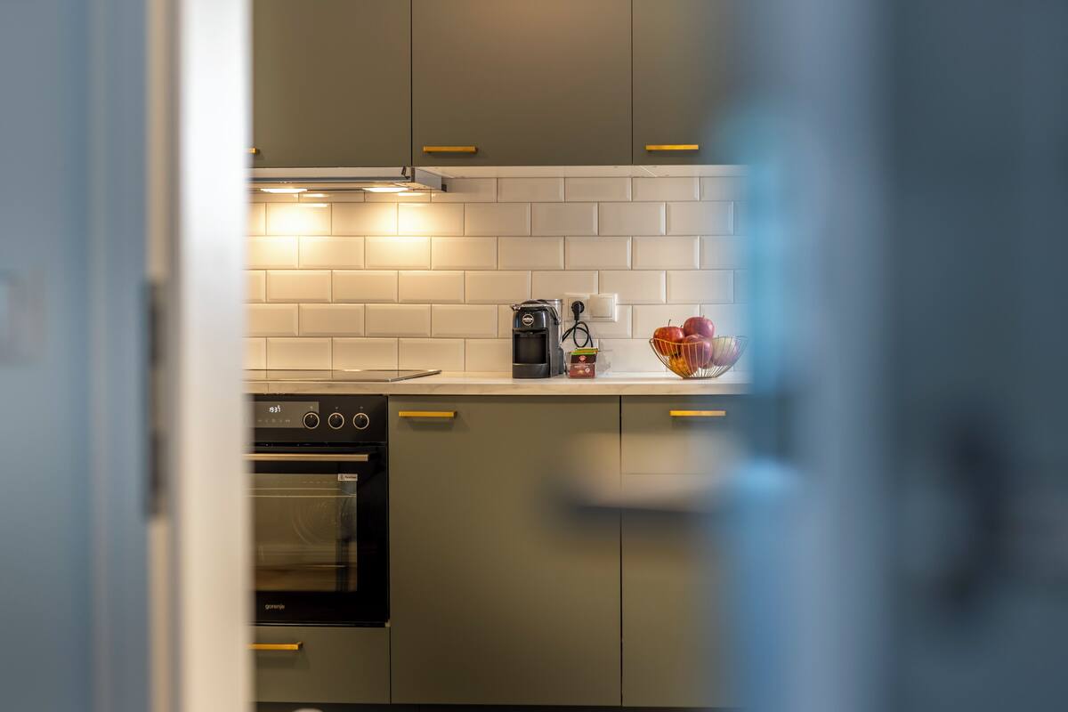 A modern kitchen with white subway tiles, stainless steel appliances, and wooden handles.