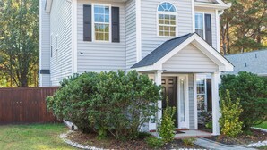 A two-story house with a front porch, a garage, and a fenced yard.