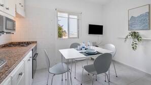 A modern kitchen with white cabinets, a granite countertop, and a dining area with a table and chairs. - Vacation 'Beach View Playa Los Cristiano' with Sea View and Wi-Fi (Arona)
