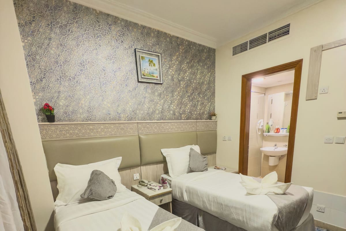 A hotel room with two beds, a bathroom visible through an open door, and a decorative wall.