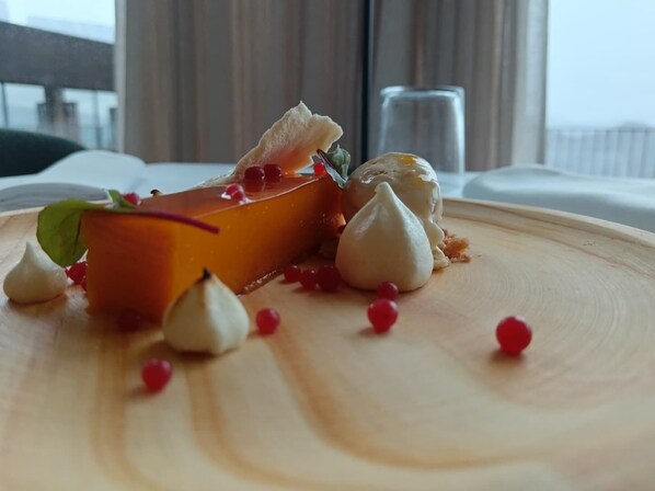 Un postre sobre un plato de madera con bayas rojas y merengues blancos.