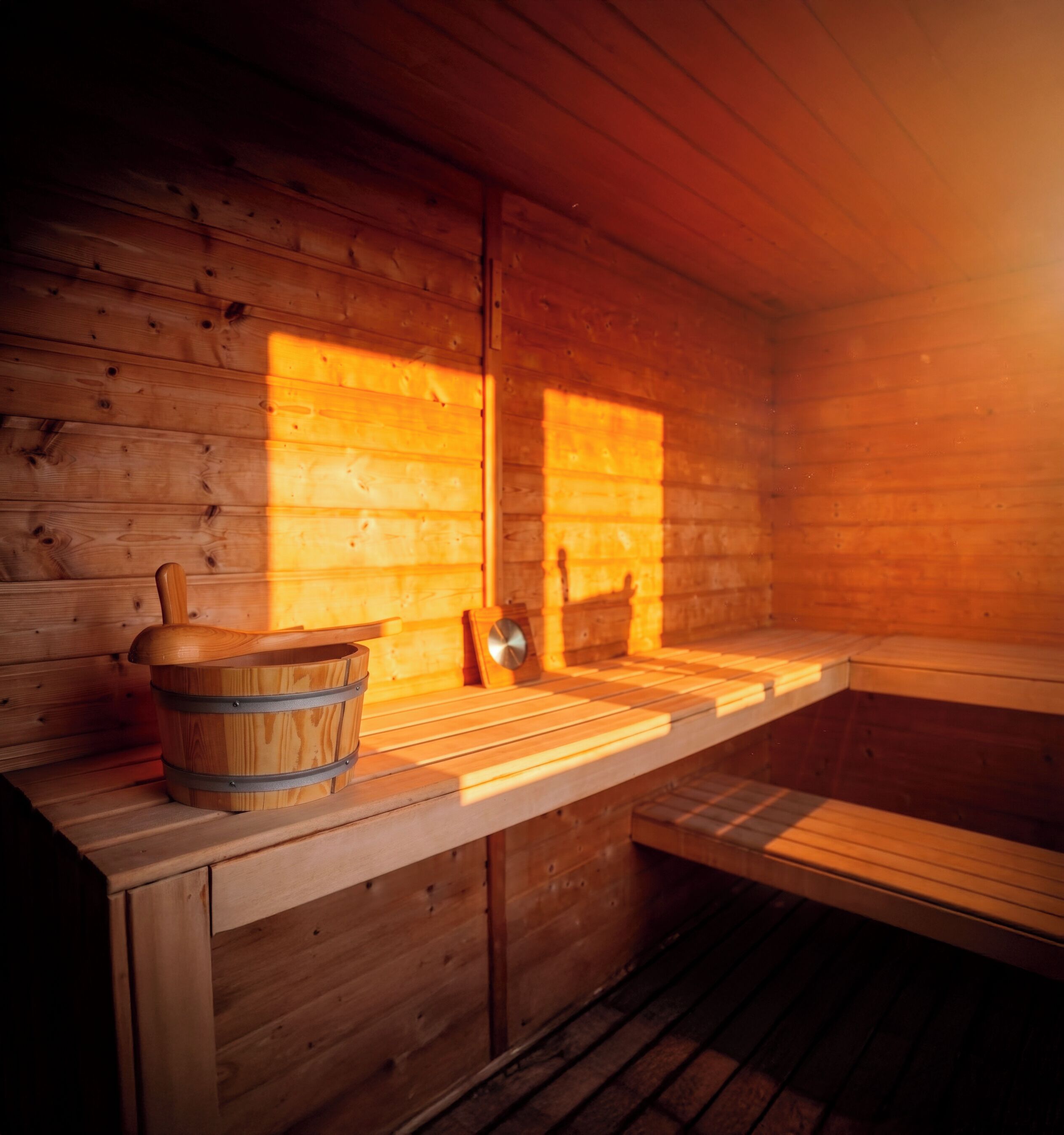 A wooden sauna with benches and a wooden bucket.