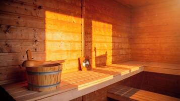 A wooden sauna with benches and a wooden bucket.