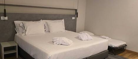 Una habitación de hotel moderna con una cama grande, una mesita de noche y un pequeño banco.