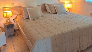 Una camera da letto con un letto grande, due lampade ai comodini, una ventola a soffitto e una finestra con tende.