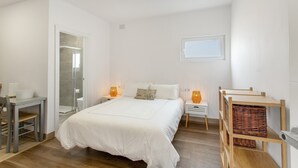 Une chambre à coucher avec un lit, des tables de chevet, un bureau et une fenêtre.