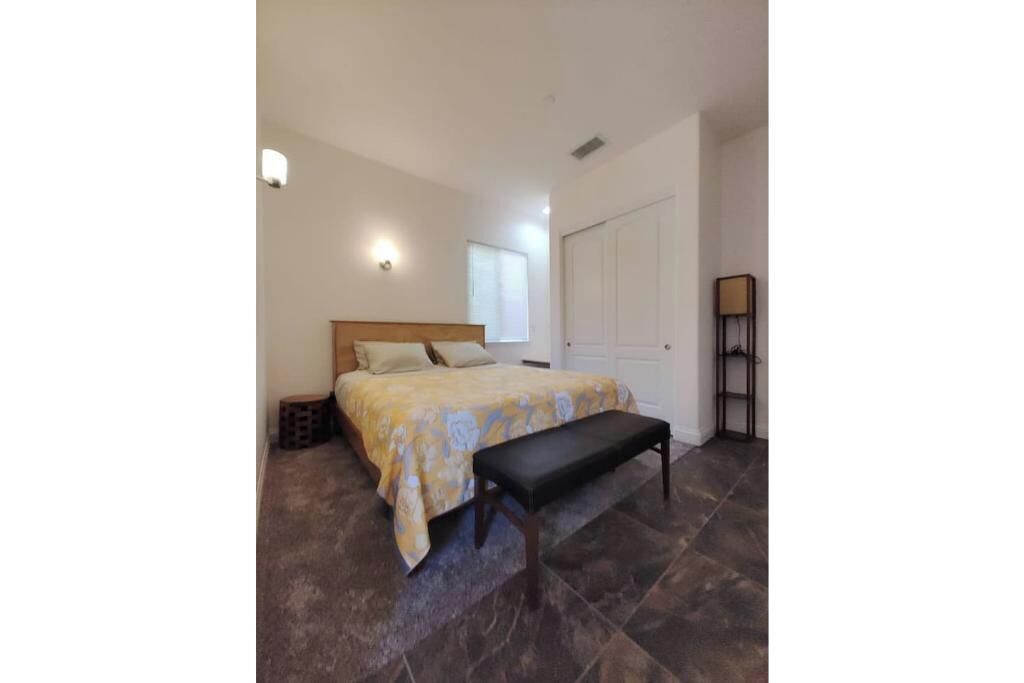 Een slaapkamer met een bed, een bankje en een garderobe.