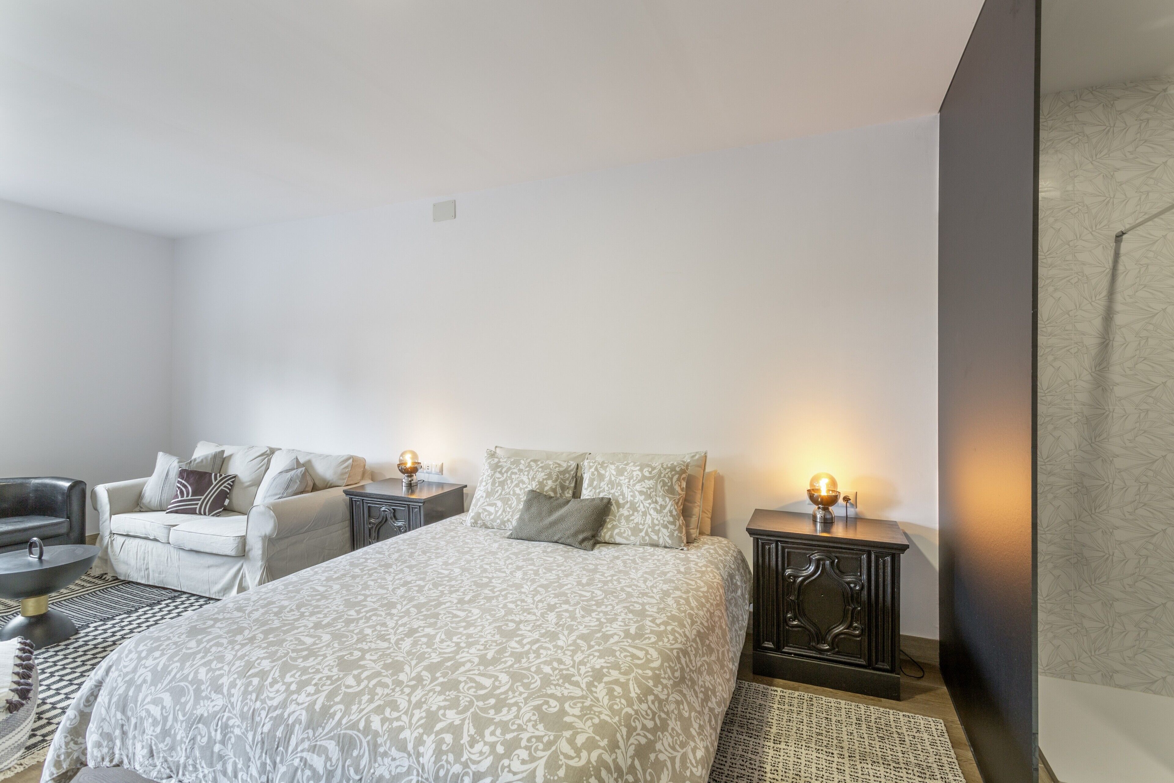 Une chambre à coucher comprenant un lit, deux tables de chevet, un canapé et un fauteuil.