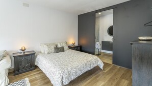 Een slaapkamer met een bed, nachtkastjes, een spiegel en een kledingkast.