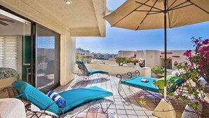 A rooftop terrace with lounge chairs, a table, and an umbrella. - Wrap-Around Patio & Pools · Terrasol Beach Resort (Cabo San Lucas)