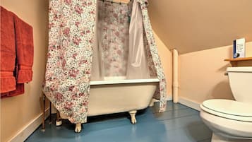 A bathroom with a bathtub, a toilet, and a shower curtain.
