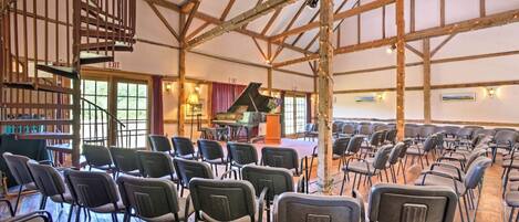 A spacious hall with a grand piano, rows of chairs, and a spiral staircase.