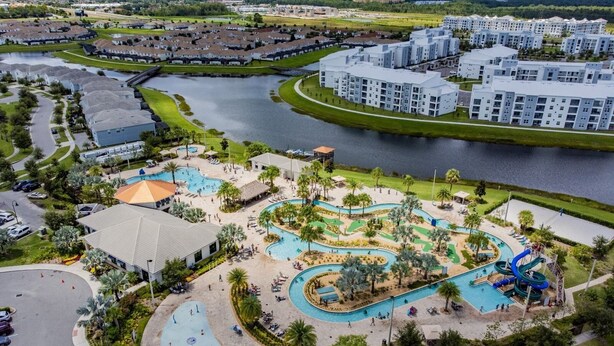 A residential area with a central swimming pool, a children's play area, and a large body of water.