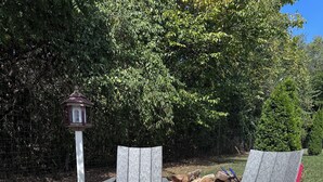 Een vuurkuil met twee Adirondack stoelen en een lantaarnpaal in een grindgebied.