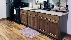 Een moderne keuken met houten kastjes, een zwarte koelkast, een magnetron en een fornuis.