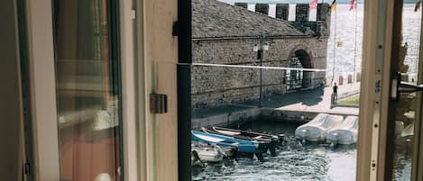Una silla junto a una ventana con vista a un canal con barcos y un puente de piedra.
