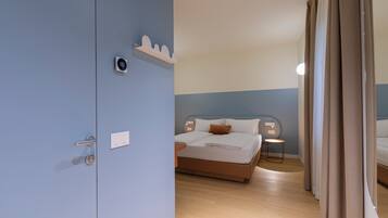 A hotel room with a bed, bedside table, and a wall-mounted thermostat.