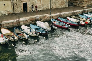 Μια σειρά από μικρά σκάφη ήταν αγκυροβολημένα σε μια προβλήτα, με ένα πέτρινο κτίριο να διακρίνεται στο βάθος.