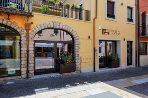 A hotel entrance with an arched doorway, a stone facade, and a sign for 'Borgo di Lazise' indicating rooms, spa, and bistro services. - Borgo di Lazise (Lazise)
