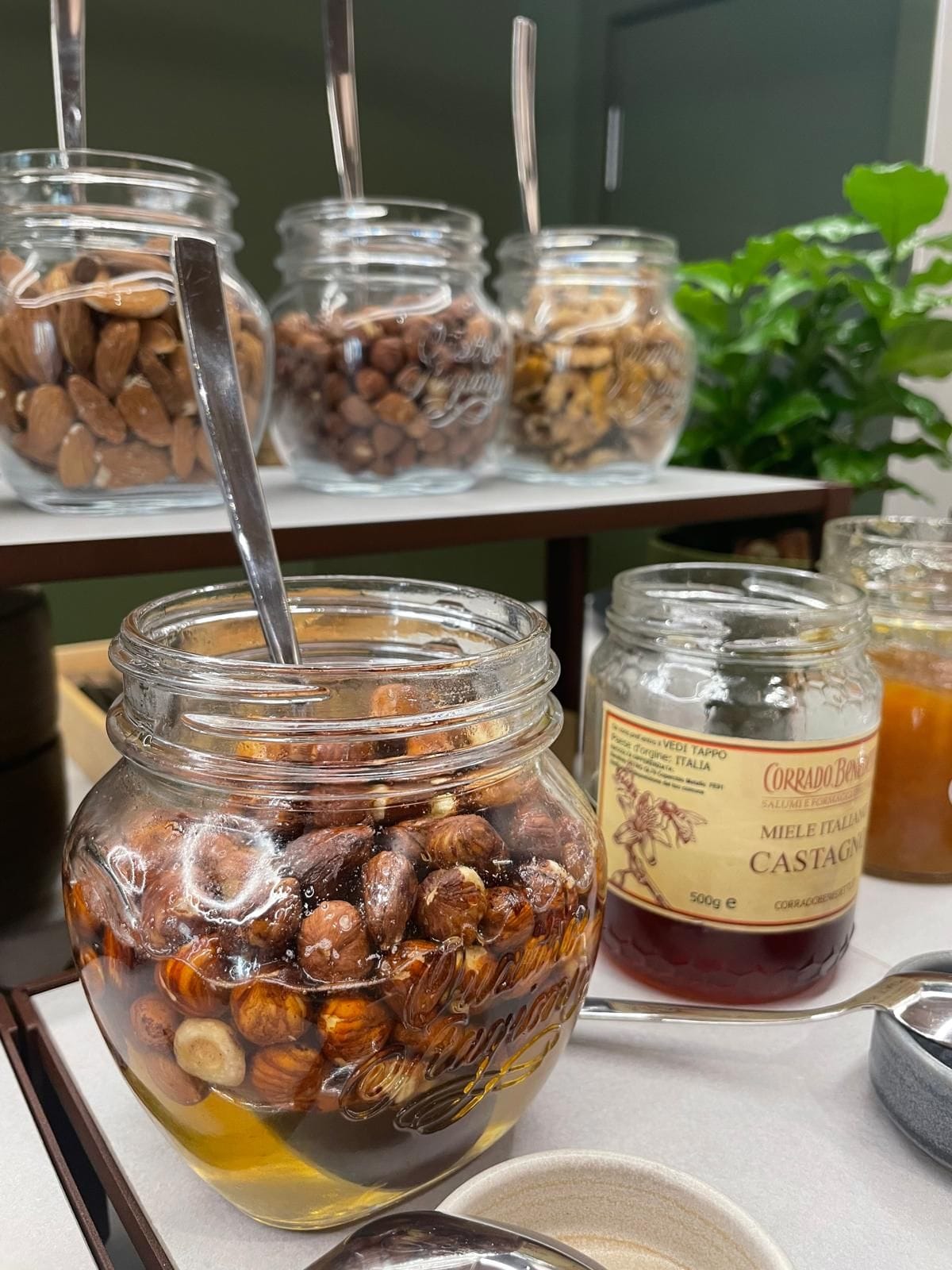 A table with jars containing various nuts and a jar of Italian chestnuts.