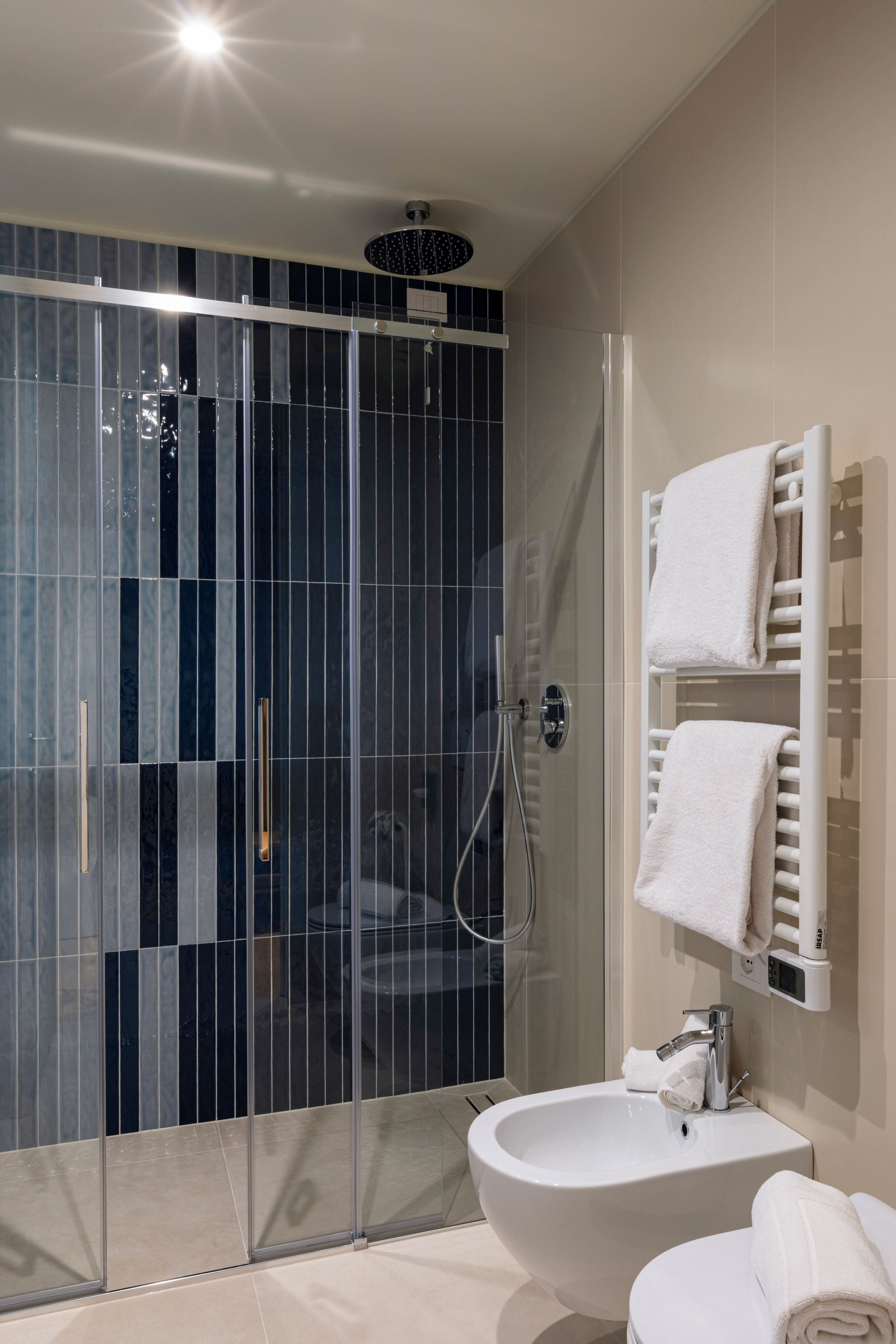 A modern bathroom with a glass-enclosed shower, a white sink, and a towel rack.